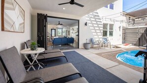 Un espacio exterior moderno con piscina, sillas de descanso y vista hacia el interior de la casa.