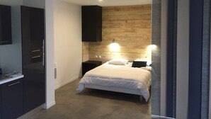 Un dormitorio con cama, mesitas de noche, armario y una pared de madera decorativa.