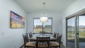 Un coin repas avec une table et des chaises, un tableau accroché au mur et une vue par la fenêtre.