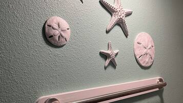 Un baño con toallero, barra de toallas en la pared y decoración de estrellas de mar y conchas marinas.