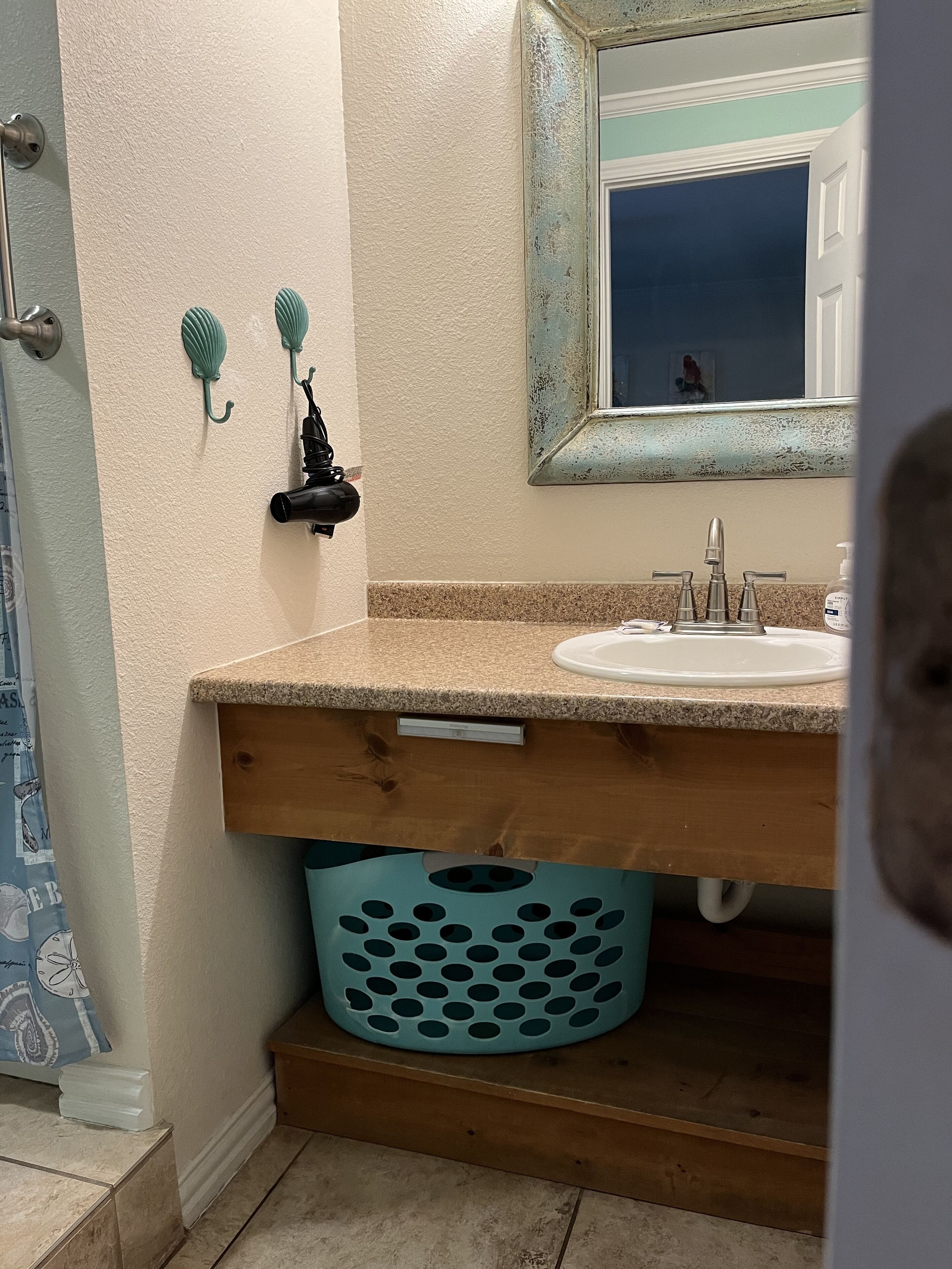 Un baño con lavamanos, espejo y tocador de madera.