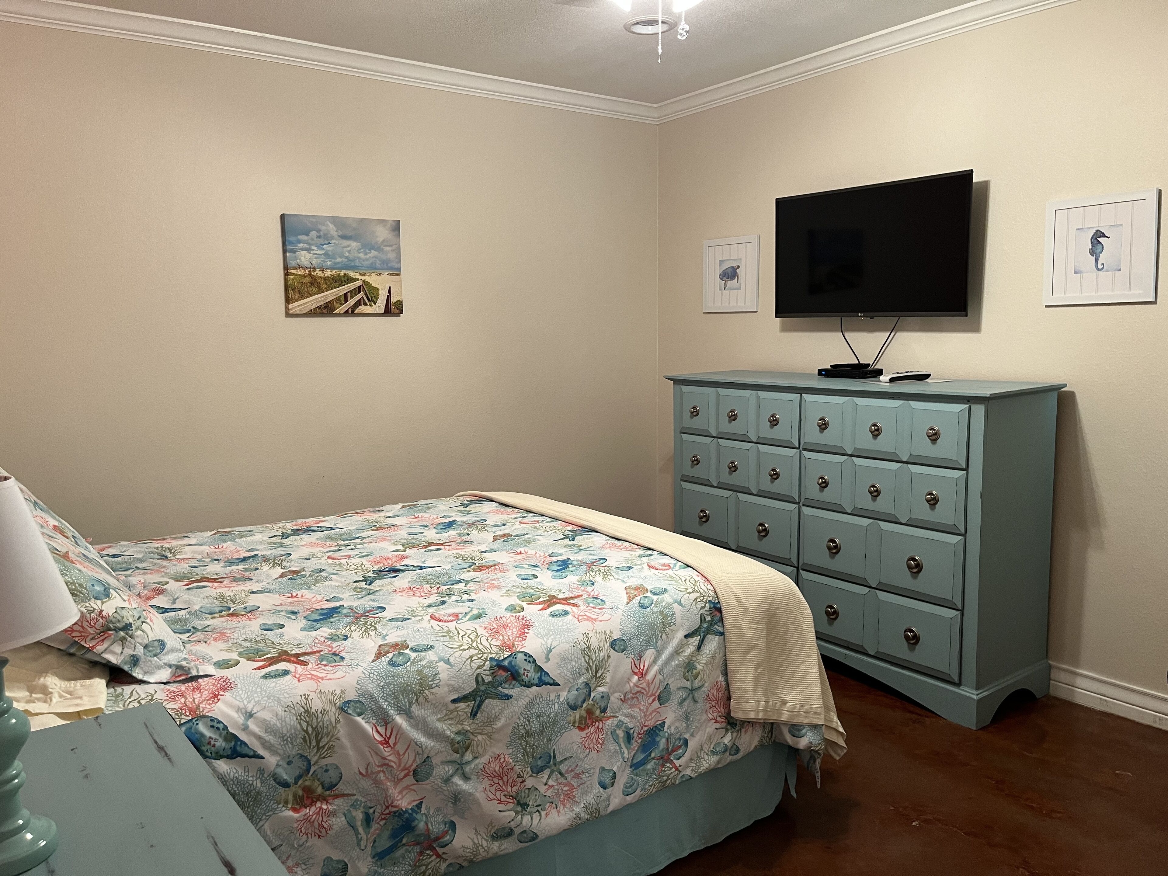 Une chambre à coucher avec un lit, une commode et un téléviseur.