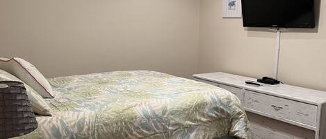 A bedroom with a bed, a TV, a ceiling fan, and a nightstand.