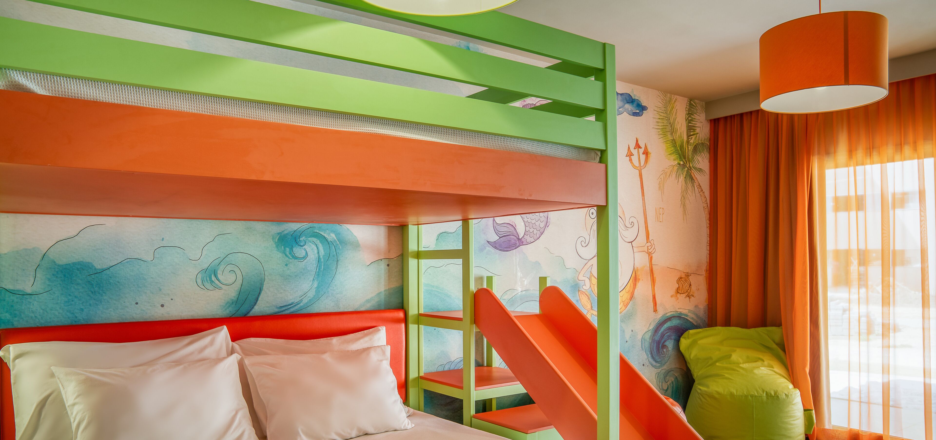 Una habitación con literas, un mural de olas marinas y una ventana con cortinas naranjas.