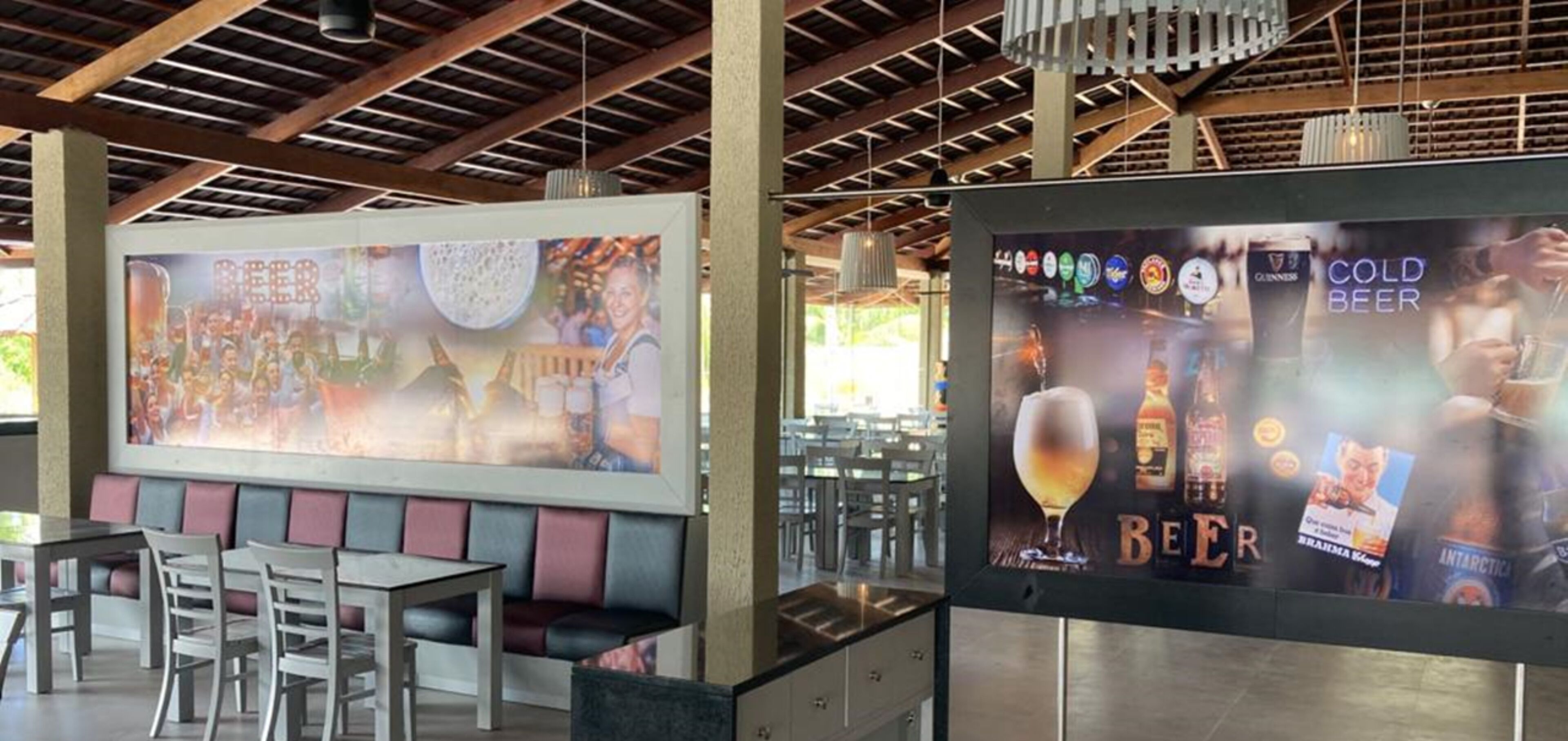 A restaurant with a large mural advertising beer, a bar area with a Guinness advertisement, and a seating area with a modern design.