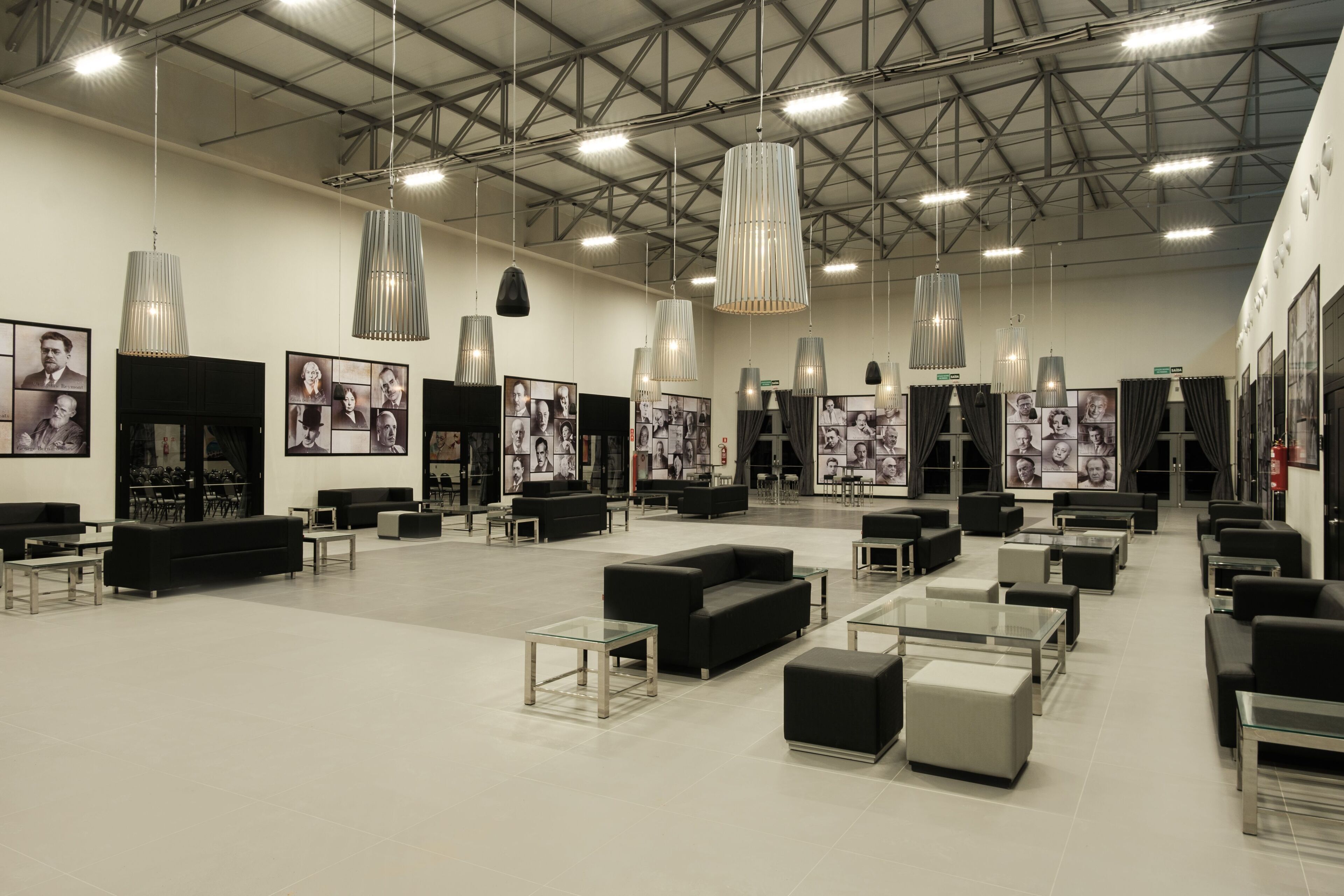 A spacious lobby with modern furniture, including sofas and tables, and large pendant lights.