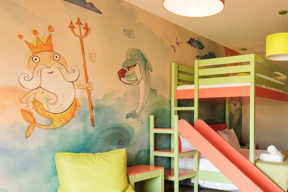 Habitación infantil con literas, un mural y una escalera.