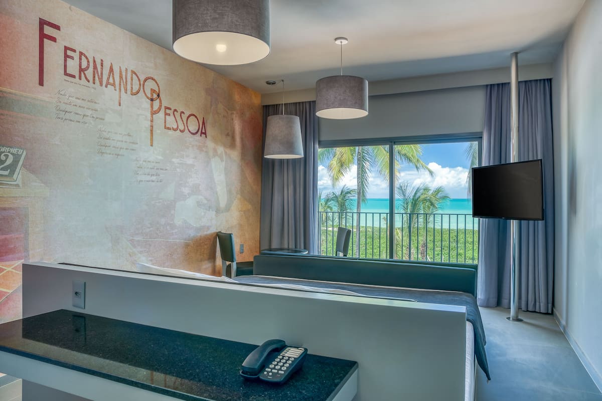 Zona de recepción de un hotel con una pared grande que muestra el nombre 'Fernando Pessoa' y un mostrador con un teléfono.