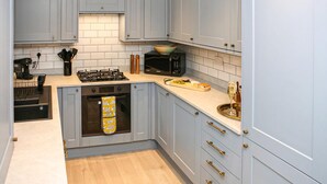 Eine moderne Küche mit hellblauen Schränken, einem Gasherd, einer Mikrowelle und einer Holz Arbeitsplatte.