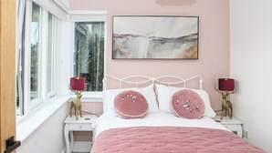Ein Schlafzimmer mit einem Bett, zwei Nachttischen, einem Fenster und einem an der Wand hängenden Bild.