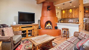 A cozy living room with a fireplace, wooden furniture, and a television.