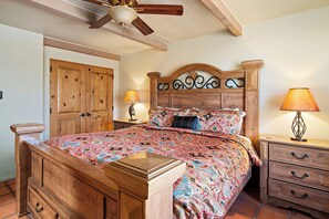 A bedroom with a wooden bed, two bedside lamps, a wooden nightstand, and a ceiling fan.