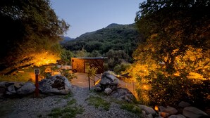 A rustic cabin with a wooden exterior, surrounded by rocks and trees, and a gravel path leading to it. - Paradise Ranch Inn Stellar House Hot-Tub,Sauna . (three rivers)