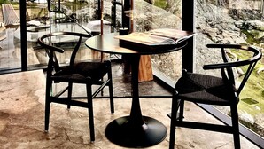 A modern interior with a round table, two black chairs, and a view of a rocky outdoor area through large windows. - Paradise Ranch Inn Stellar House Hot-Tub,Sauna . (three rivers)