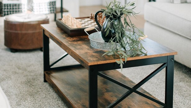 Una sala de estar con una mesa de centro de madera, un reloj en la pared y un sofá blanco.