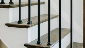 Una escalera con escalones de madera y barandas de metal negro.