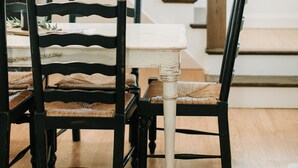 Un comedor con una mesa y sillas de madera, una escalera con barandillas negras, y un ventanal con luz natural.