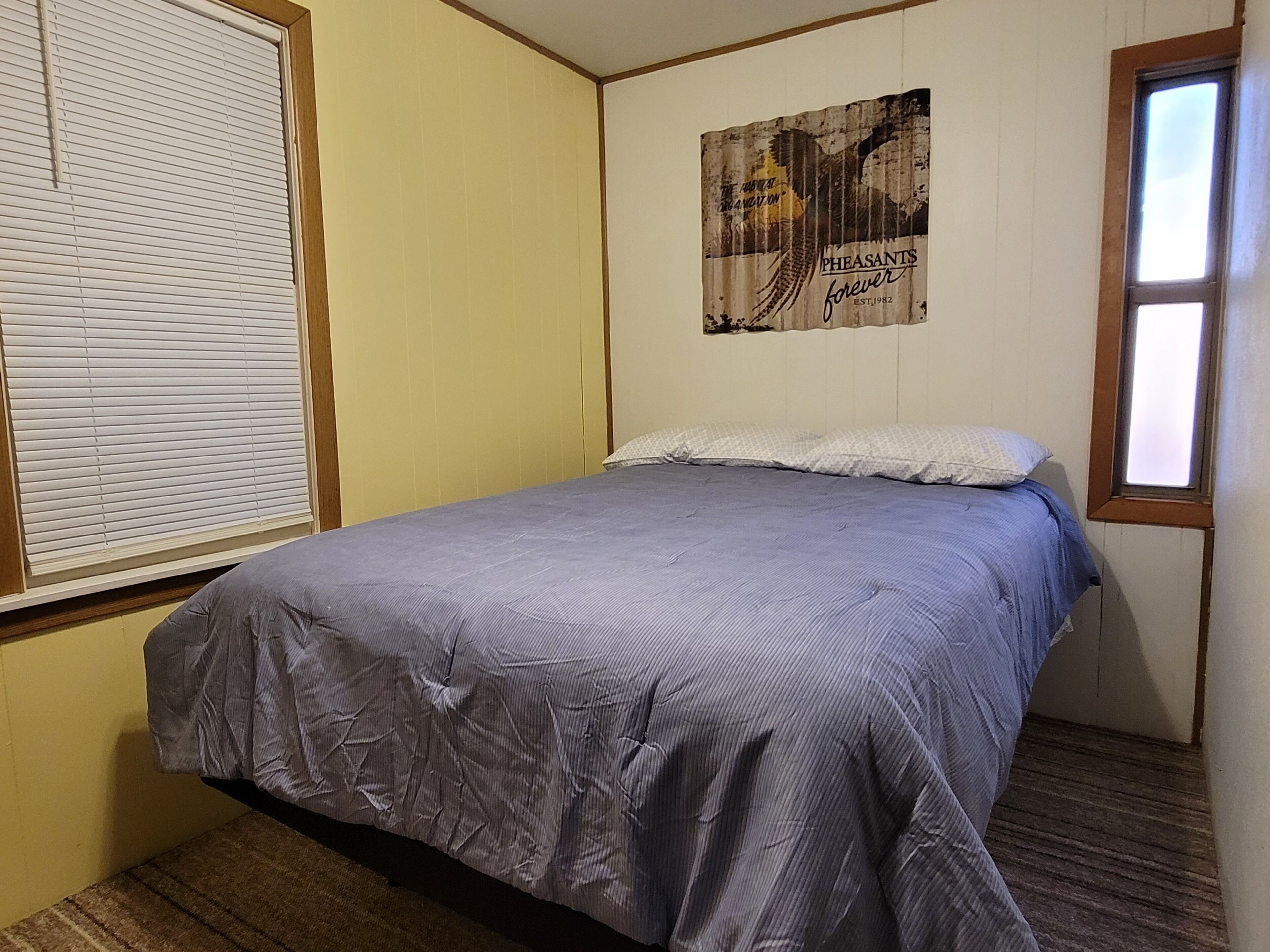 A bedroom with a single bed, a window, and a wall poster.