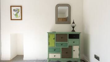 A green dresser with multiple drawers and a mirror above it.