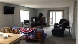 A living room with a fireplace, a television mounted on the wall, and a dining area with a table and chairs. - Great Location, walk to the Flume 1.5 mi and trailheads (Lincoln)