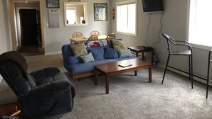 A living room with a sofa, armchair, coffee table, and a television. - Great Location, walk to the Flume 1.5 mi and trailheads (Lincoln)