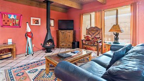 Ein gemütliches Wohnzimmer mit Kamin, Fernseher und bequemen Sitzgelegenheiten.