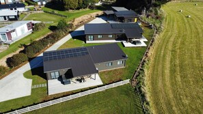Un quartier résidentiel avec des maisons modernes dotées de panneaux solaires, d’une pelouse bien entretenue et d’un ciel dégagé.