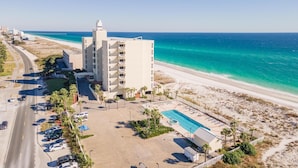 Un hôtel de grande hauteur doté d’une piscine et offrant une vue sur la plage, situé à proximité d’une route et de la plage.