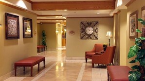 A hotel lobby with a wooden ceiling, a clock on the wall, and a seating area with a bench and a chair.