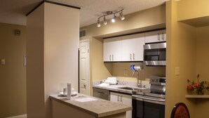 A modern kitchen with white cabinets, stainless steel appliances, and a marble countertop.