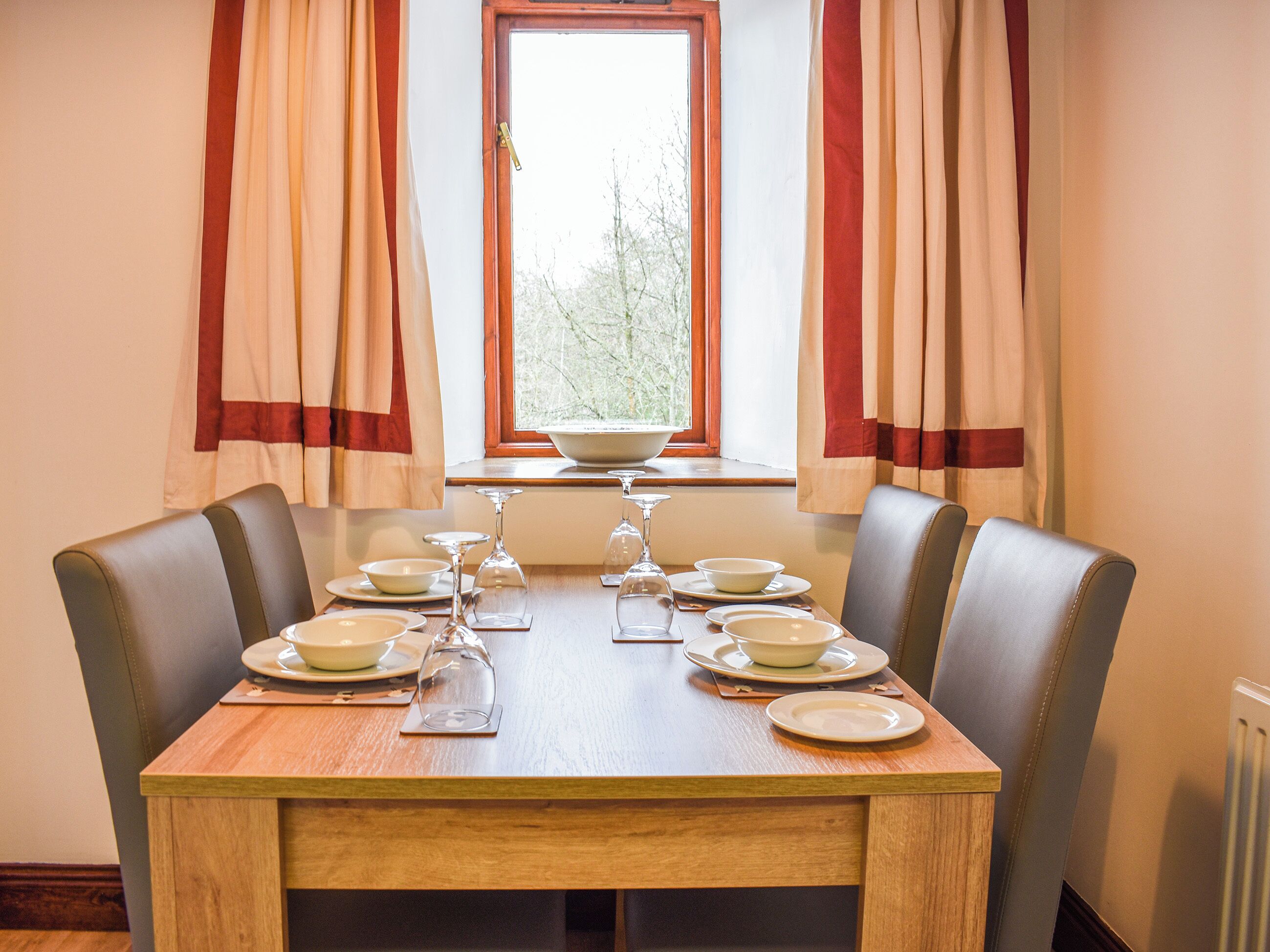 Une table à manger dressée pour six personnes, avec des assiettes, des verres et un saladier.