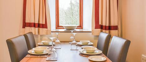 Une table à manger dressée pour six personnes, avec des assiettes, des verres et un saladier.
