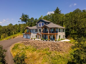 Une grande maison à deux étages, dotée de nombreux balcons, d’un garage et de fondations en pierre.