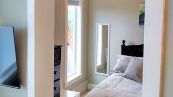 Ein Schlafzimmer mit Bett, Kommode, Schreibtisch und Fenster.