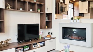 Una sala moderna con una televisión de pantalla plana, una chimenea, estanterías de madera y un comedor con mesa.