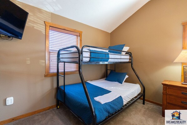 A bunk bed room with a television, a window with blinds, and a wooden dresser. - 6BR Branson Lodge | 6 King Rooms | Near Silver Dollar City + Pools (FHL-263WO) (Branson)