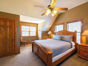 Ein Schlafzimmer mit einem hölzernen Bett, zwei Nachttischen mit Lampen, einem Deckenventilator und einem Fenster mit Jalousien.