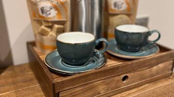 A wooden tray with two ceramic cups and a thermos, placed on a table.