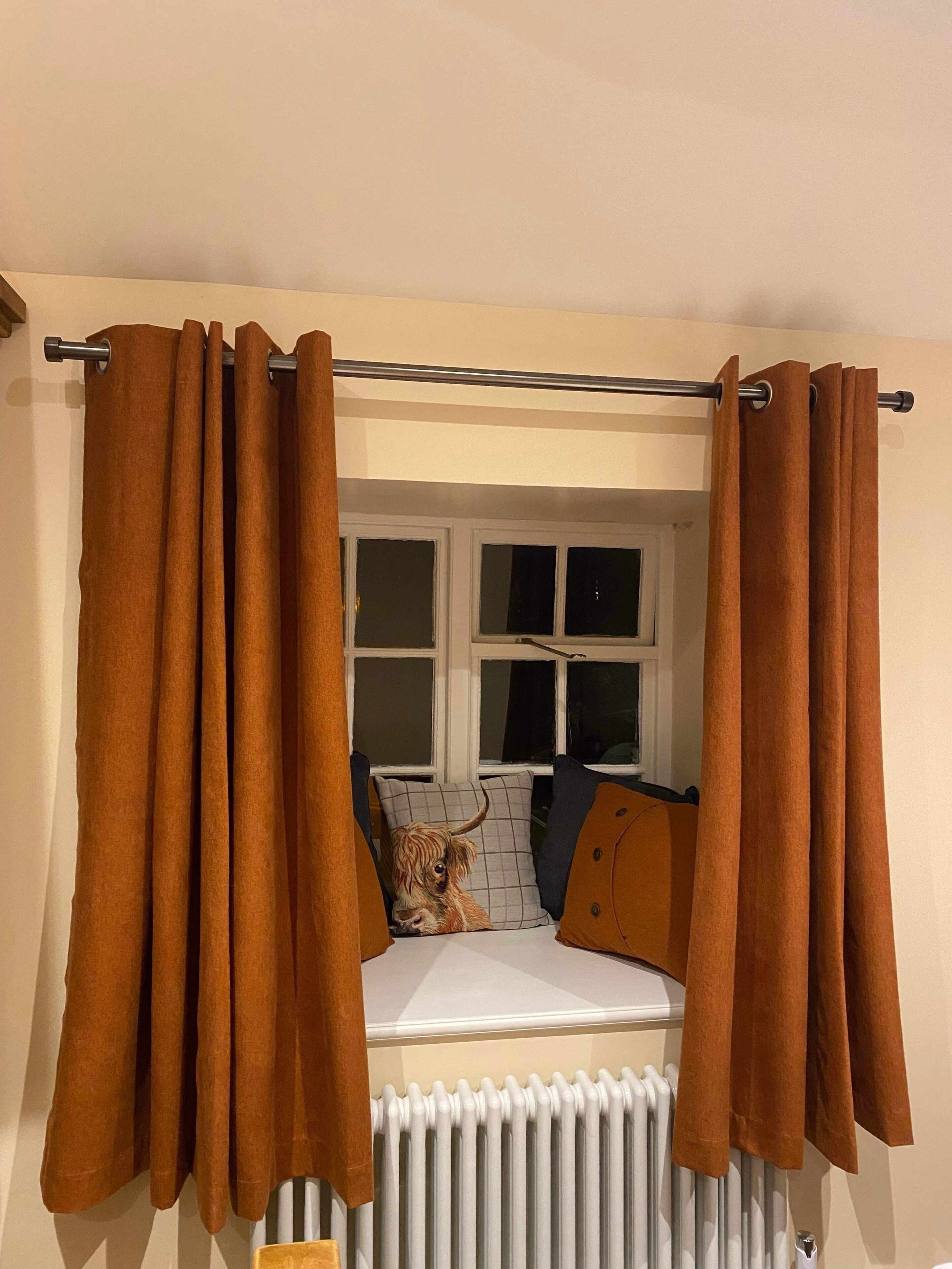 Una habitación con ventana, radiador y cortinas marrones.