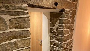 A stone wall with a wooden door and a small step leading into a room. - Bulls Head - Holymoorside (Chesterfield)