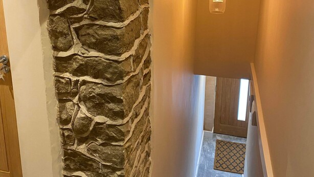 A stone wall with a wooden beam ceiling and hanging pendant lights. - Bulls Head - Holymoorside (Chesterfield)