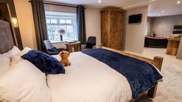 A hotel room with a large bed, a wooden wardrobe, a desk with a chair, and a television mounted on the wall.