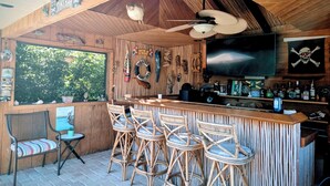Tiki-tyylinen baari, jossa on puuseinät, baaritiski ja useita rottinkituoleja.