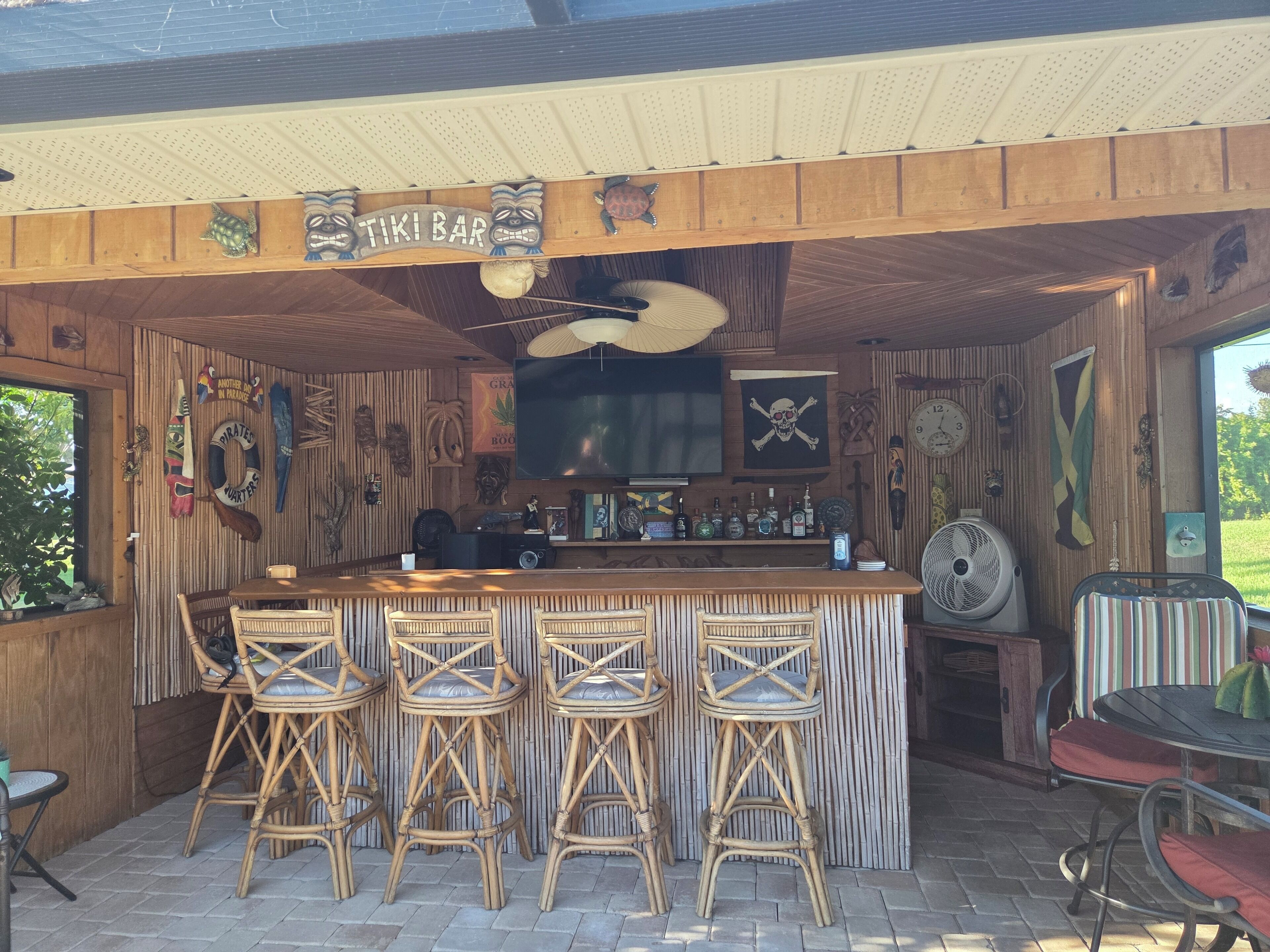 Un bar de style tiki avec un décor intérieur en bois, des tabourets de bar, un grand téléviseur et diverses décorations.