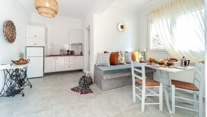 Una cocina moderna con armarios blancos, una zona de comedor con banco y una mesa con sillas.