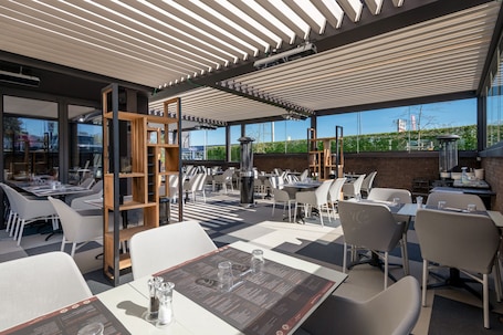 An outdoor dining area with tables and chairs, a wooden bookshelf, and a view of the cityscape.. Hotel Le 830