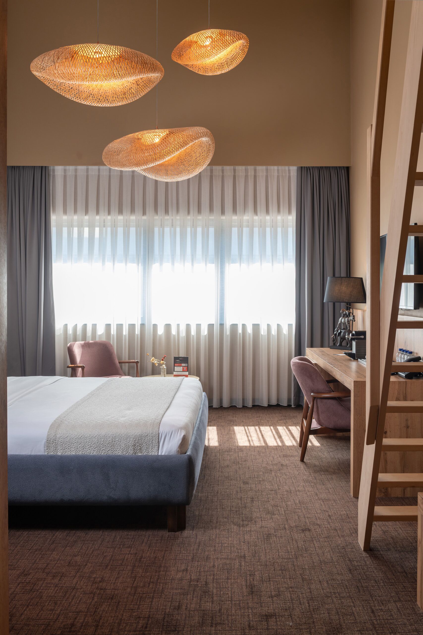 A hotel room with a bed, a desk, a chair, a lamp, and a TV.