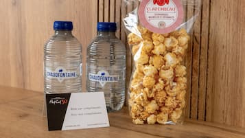 Due bottiglie d'acqua Chaud Fonteine, una confezione di snack gourmet Clarembeau e un biglietto di benvenuto dell'hotel.