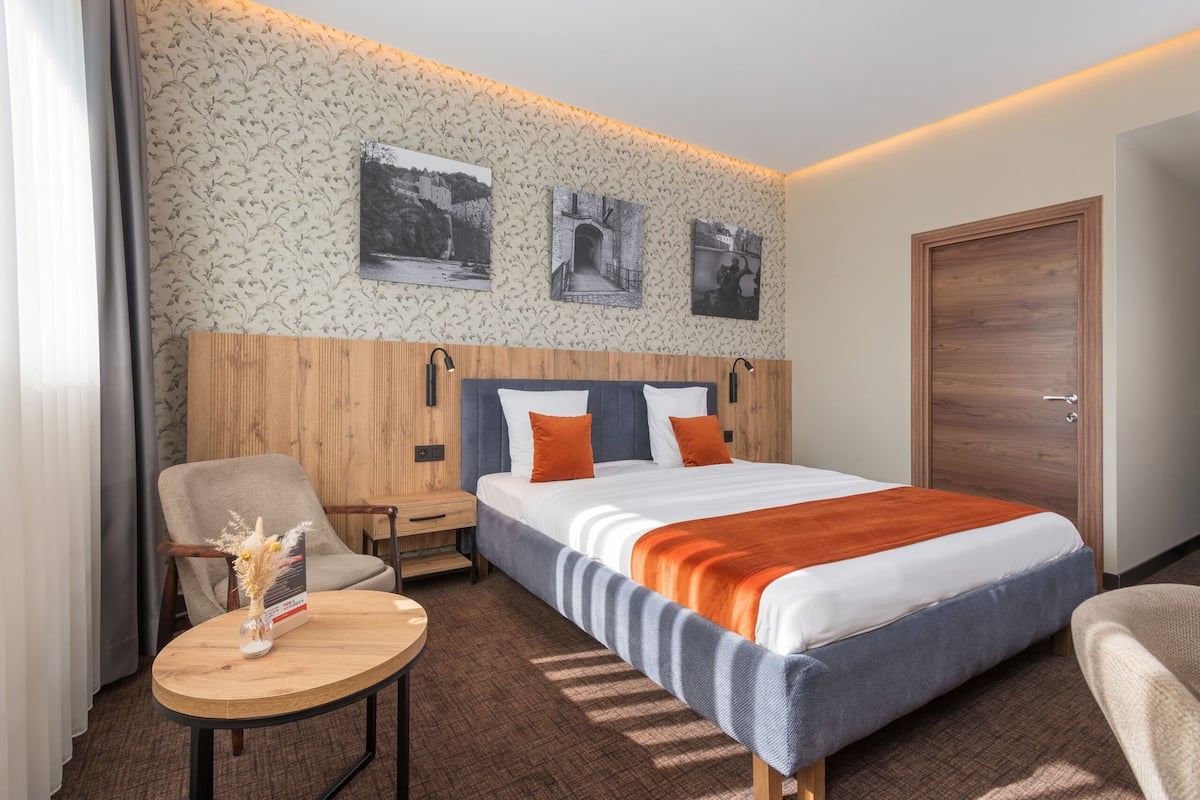 Une chambre d’hôtel avec un lit, une chaise, une petite table et une porte en bois.