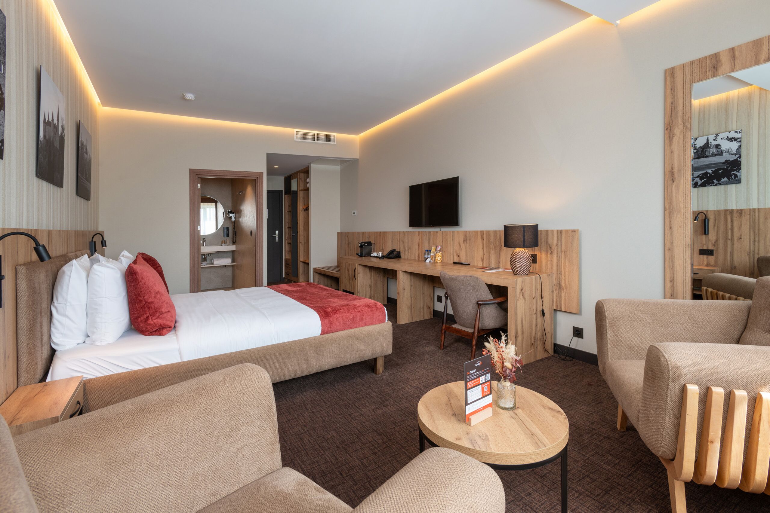 Une chambre d’hôtel avec un lit, un bureau, une télévision, une chaise et un canapé.